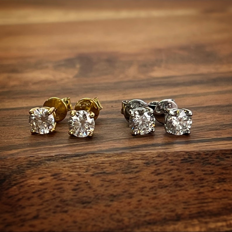 May include: Two pairs of earrings with round clear stones. One pair has gold posts and the other pair has silver posts.