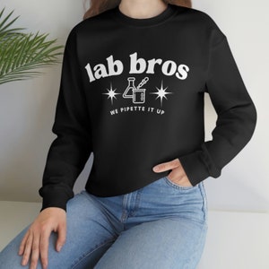 May include: Black sweatshirt with white text that reads "lab bros" and a beaker with a pipette inside. Below the beaker is the text "we pipette it up".
