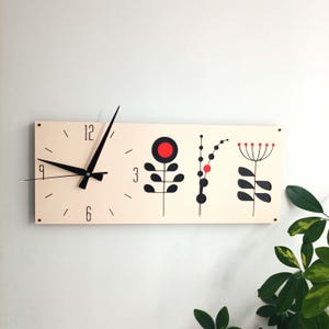Peut inclure: Une horloge murale rectangulaire avec un fond crème. L'horloge présente des aiguilles noires et des motifs floraux minimalistes noirs et rouges. Les chiffres 3, 6, 9 et 12 sont marqués. L'horloge est fixée sur un mur blanc.