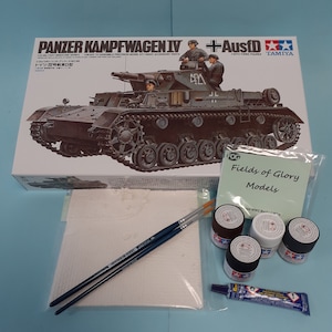 May include: A model kit of a German Panzerkampfwagen IV tank with Ausf D variant. The box art features a detailed illustration of the tank in a desert setting. The kit includes three figures, a Tamiya logo, and the words "Panzerkampfwagen IV + Ausf D".