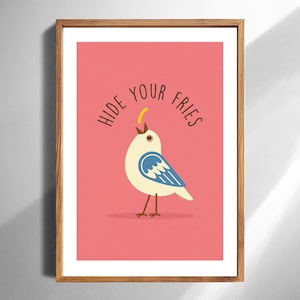 May include: A framed art print featuring a cartoon bird with blue wings and a yellow beak, set against a pink background. The text "HIDE YOUR FRIES" is arched above the bird. The frame is made of wood.