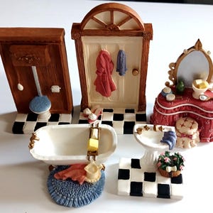 Peut inclure: Un ensemble de cinq figurines miniatures représentant des meubles de salle de bain et de chambre, incluant des toilettes, une porte avec des peignoirs, une coiffeuse avec miroir, une baignoire avec tapis bleu et un lavabo sur pied, sur socles carrelés.
