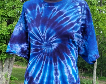 Op de afbeelding: Een blauw en zwart tie-dye T-shirt met een spiraalpatroon.