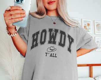 May include: A gray oversized t-shirt with a black graphic that says "Howdy Y'all" with a cowboy hat graphic.