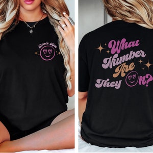 May include: Black t-shirt with a pink and white graphic on the front that says "Dance Mom" and a pink and white graphic on the back that says "What number are they on?"