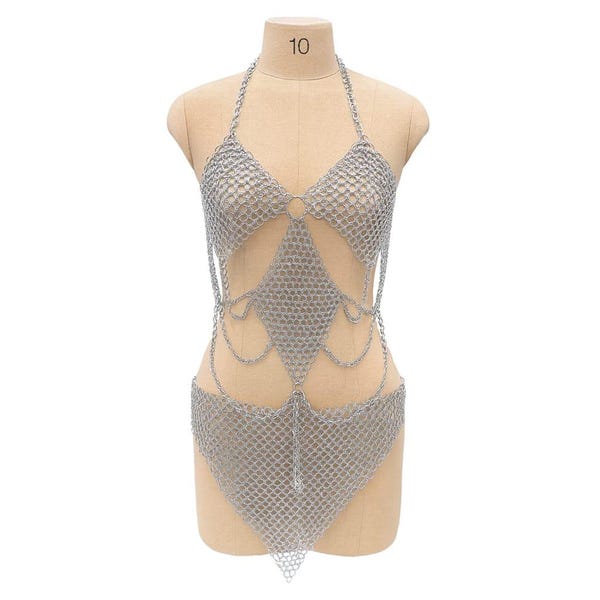 May include: Silver chainmail bodysuit displayed on a mannequin. The halter-style top and high-waisted bottom are connected by a diamond-shaped design. The garment is made of small, interconnected metal rings.
