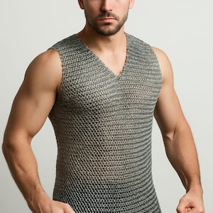 May include: A silver chainmail vest with a V-neck design. The sleeveless garment is made of small, interlocking metal rings. The vest is worn over the torso and shoulders. The overall theme is medieval or fantasy attire.