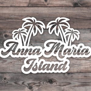 May include: White wooden sign featuring the text "Anna Maria Island" in a decorative font, with palm tree silhouettes above. The sign is set against a rustic, weathered wood background.