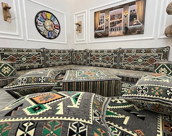 May include: A gray and green patterned sectional sofa with multiple matching throw pillows. The sofa is arranged in a U-shape and is set on a gray carpet.