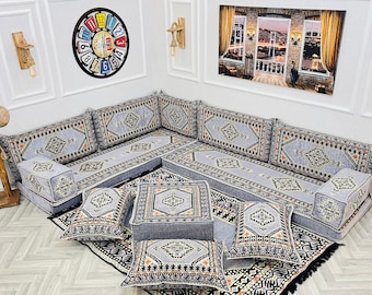 May include: A gray and white patterned floor seating set with multiple cushions and pillows. The set is arranged in a corner of a room with a gray and white patterned rug.