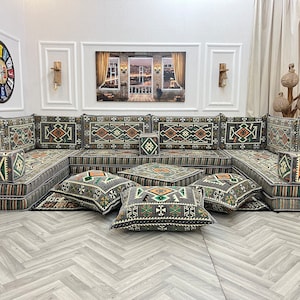 Könnte beinhalten: Ein graues und grünes, gemustertes Ecksofa mit mehreren Kissen. Das Sofa ist U-förmig angeordnet und hat ein traditionelles Design.