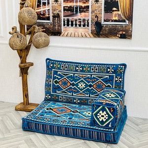 May include: A blue and orange patterned floor cushion with a matching back cushion and a smaller square cushion. The cushions are made of a soft, woven fabric and have a fringe trim.