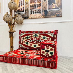 Peut inclure: Un ensemble de coussins de sol rouges avec un dossier assorti et un petit ottoman cubique. L'ensemble présente un motif géométrique en blanc, vert et rouge. Le coussin de sol a une bordure rayée.