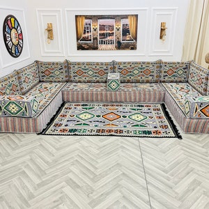 May include: A gray and white patterned sectional sofa with a matching rug. The sofa is made up of individual cushions and has a traditional design.