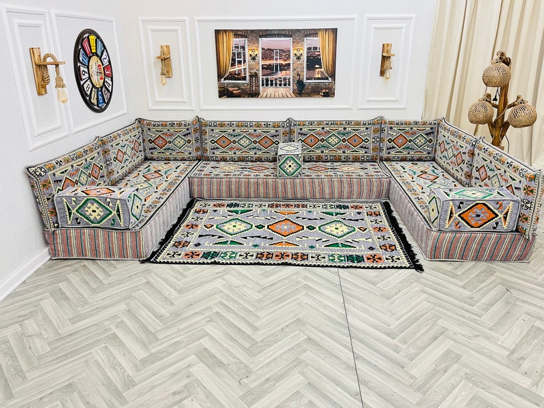 May include: A gray and white patterned sectional sofa with a matching rug. The sofa is made up of individual cushions and has a traditional design.