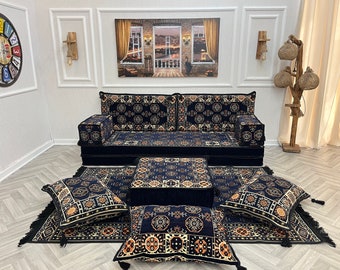 May include: A dark blue sofa set with patterned cushions and a matching rug. The set includes a sofa, two armrests, a coffee table, and several throw pillows. The cushions and rug feature a repeating geometric design in shades of blue, beige, and orange.
