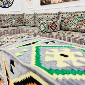 May include: A traditional Moroccan seating set with gray and beige cushions featuring intricate geometric patterns. The cushions are arranged in a square shape with a smaller gray and beige cushion in the center.