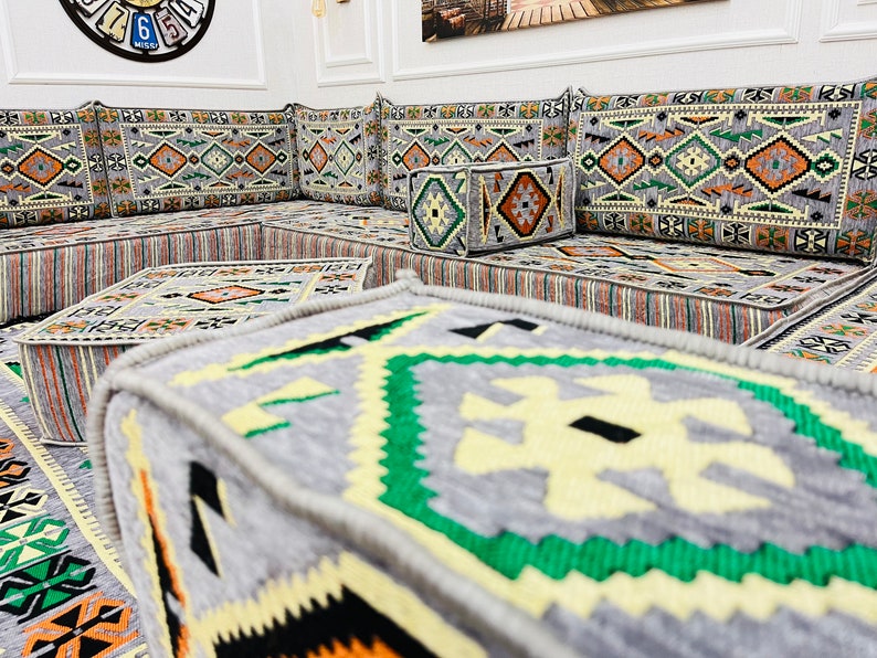 May include: A traditional Moroccan seating set with gray and beige cushions featuring intricate geometric patterns. The cushions are arranged in a square shape with a smaller gray and beige cushion in the center.