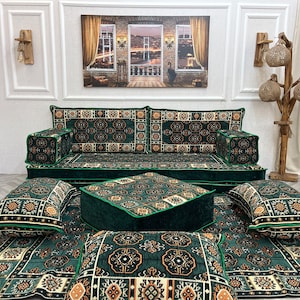 Könnte beinhalten: Ein grünes Sofa mit goldenen Mustern, dazu passende Kissen und ein grüner Hocker. Das Sofa steht auf einem grünen Teppich mit goldenen Mustern.