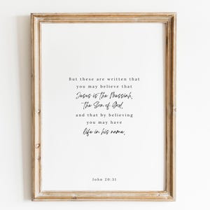 May include: A framed print with a white background and black text. The text reads "But these are written that you may believe that Jesus is the Messiah, The Son of God. And that by believing you may have life in his name. John 20:31".