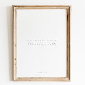 May include: A framed print with a beige wood frame. The print features the text "Let everything that has breath Praise the Lord" in a cursive font. The text "Psalm 150:6" is printed below the quote.
