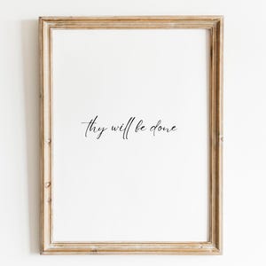 Puede incluir: Una impresión enmarcada con el texto "Hágase tu voluntad" en una fuente simple y elegante.