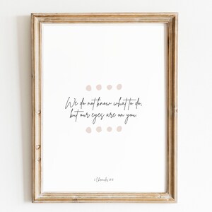 Op de afbeelding: Een printbaar wanddecor ontwerp met een witte achtergrond en zwarte tekst die luidt "We weten niet wat we moeten doen, maar onze ogen zijn op jou gericht." De tekst wordt omringd door een cirkel van kleine, lichtbruine stippen. De onderkant van het ontwerp bevat de tekst "2 Kronieken 20:12".