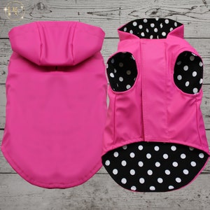 May include: Pink dog raincoat with a hood and a black and white polka dot lining. The raincoat is waterproof and has a zip closure.