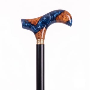 Könnte beinhalten: Ein Gehstock mit einem glatten schwarzen Schaft und einem dekorativen Griff aus einer Kombination von natürlichem braunem Maserholz und wirbelndem metallisch blauem Harz. Ein goldfarbener Metallring mit geprägtem Muster verbindet den Griff.