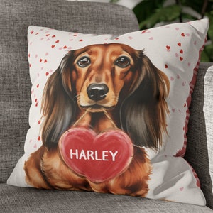 May include: A white throw pillow with a red heart and the name "HARLEY" printed on it. The pillow features a watercolor illustration of a brown and black dachshund dog holding the heart.