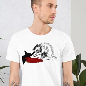 May include: A white t-shirt with a black and white illustration of a cat with a red splatter on the ground. The cat is looking down at the splatter.