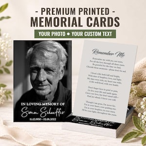 May include: A stack of rectangular memorial cards featuring a black and white portrait of an older person with the text In Loving Memory of Simon Schaeffer 11.12.1950 - 02.01.2022 and a white card with the poem Remember Me printed in black text.
