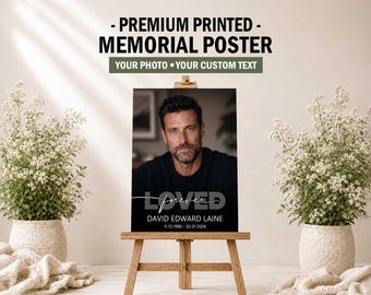 May include: A rectangular memorial poster displayed on a wooden easel. The poster features a portrait of a man, the word LOVED in large letters, the script word forever, and the text DAVID EDWARD LAINE 11.12.1980 - 02.01.2026 at the bottom.