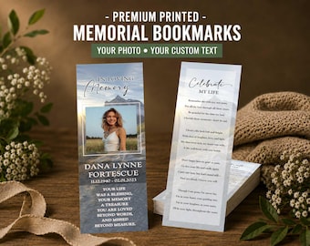 May include: Two rectangular memorial bookmarks featuring a mountain landscape background. The left bookmark displays a photo of a person, the text IN LOVING MEMORY, DANA LYNNE FORTESCUE, dates 11.12.1940 - 02.01.2023, and a poem. The right bookmark shows CELEBRATE MY LIFE and a poem.
