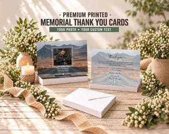 May include: A stack of memorial thank you cards featuring a mountain road landscape, a portrait of a person, and the text "TROY ROBERT SHALLCROSS". The cards include a "Thank you" message and are accompanied by a stack of white envelopes.