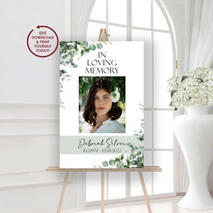 May include: A memorial sign on an easel with the text "In Loving Memory" above a portrait of a woman. The sign includes the name "Deborah Silver" and dates 11.12.1970 - 02.01.2022, with eucalyptus and floral accents. The sign also has the text "EDIT DOWNLOAD & PRINT YOURSELF TODAY!"