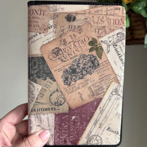 May include: A book cover with a collage of vintage ephemera, including old letters, stamps, and botanical illustrations. The cover has a black border and a mix of beige, brown, and burgundy tones. The text on the cover is in a variety of fonts.