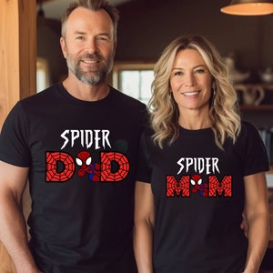 Puede incluir: Dos camisetas negras con un gr&aacute;fico de Spider-Man y el texto "Spider Dad" y "Spider Mom" impreso en ellas.