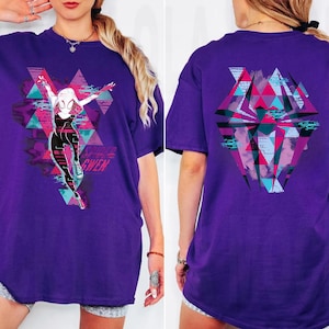 May include: A purple t-shirt featuring a graphic of a superheroine in a dynamic pose, with the name "GWEN" below. The design incorporates geometric shapes and vibrant colors. The back of the shirt has a similar geometric design.