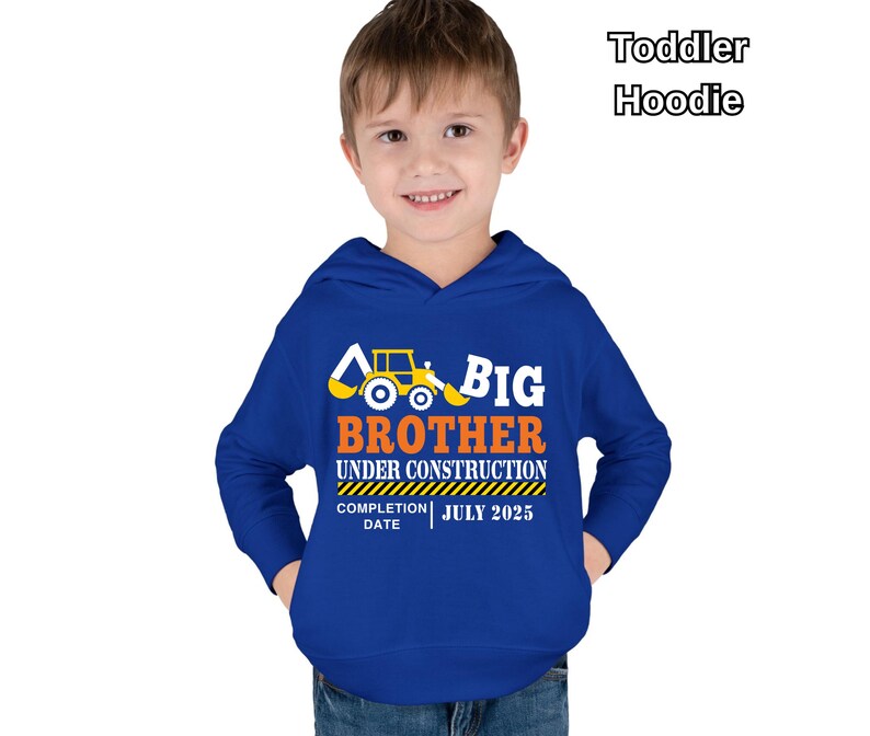 May include: A royal blue toddler hoodie with the words "BIG BROTHER UNDER CONSTRUCTION" in white and orange, along with a yellow construction vehicle graphic. The completion date is July 2025.