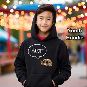 Puede incluir: Sudadera con capucha negra para j&oacute;venes, con bolsillo de canguro y capucha. La sudadera presenta un bocadillo blanco con la palabra "BOOP" y un dibujo de ara&ntilde;a. Tambi&eacute;n se ve el texto "Youth Hoodie".
