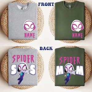 Op de afbeelding: Grijze en olijfgroene sweatshirts met een Spider-Gwen-ontwerp. De voorkant van de shirts toont het masker van het personage en het woord "NAME". De achterkant van de shirts zegt "SPIDER-SOS" en "SPIDER-MOM" met een cartoonafbeelding van Spider-Gwen.
