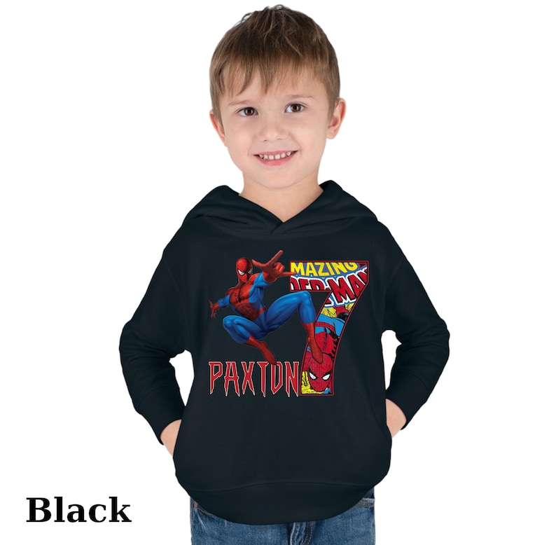Puede incluir: Sudadera con capucha negra con un gr&aacute;fico de Spiderman en estilo de c&oacute;mic. El gr&aacute;fico incluye el texto "Amazing Spiderman" y el n&uacute;mero "7". El texto "Paxton" tambi&eacute;n est&aacute; incluido en el gr&aacute;fico.