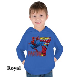 Puede incluir: Una sudadera con capucha azul real con un gr&aacute;fico de Spiderman en estilo de c&oacute;mic. El gr&aacute;fico incluye el texto "Amazing Spiderman" y el n&uacute;mero "7". El texto "Paxton" tambi&eacute;n est&aacute; incluido en la sudadera.