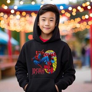 Puede incluir: Sudadera con capucha negra con un gr&aacute;fico de Spiderman en un traje rojo y azul, el texto "Amazing Spiderman" y el nombre "Josiah" impreso en la parte delantera.
