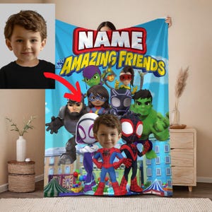 May include: A personalized blue blanket featuring the text "NAME and his AMAZING FRIENDS" with cartoon superhero characters. The blanket has a photo of a child's face in the center, with a red arrow pointing to the superhero characters.