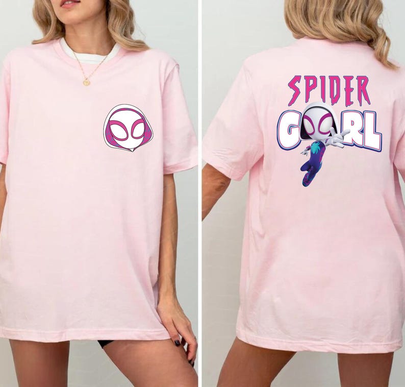 Op de afbeelding: Lichtroze T-shirt met een Spider-Gwen ontwerp. De voorkant van het shirt toont een witte en paarse masker afbeelding. De achterkant van het shirt heeft de woorden "SPIDER GIRL" in paars, met een afbeelding van Spider-Gwen.