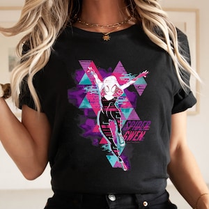 May include: Black t-shirt featuring a graphic of Spider-Gwen in a dynamic pose, set against a backdrop of purple, pink, and teal geometric shapes. The words "Spider-Gwen" are printed in a stylized font.