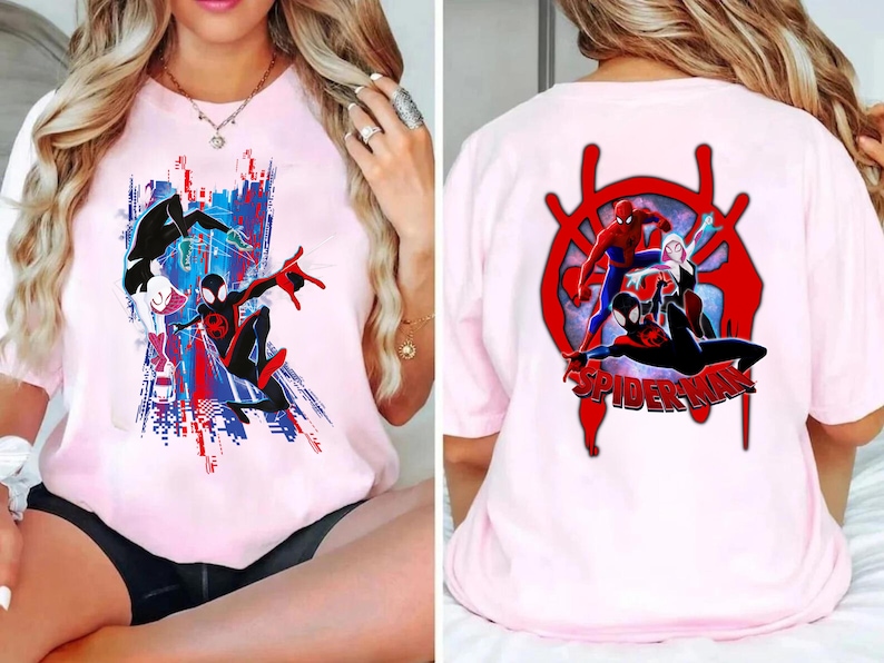 May include: Pink t-shirt featuring Spider-Man characters. The front graphic shows Spider-Man in action with a cityscape backdrop in red, white, and blue. The back displays a red Spider-Man logo with multiple Spider-Man characters and the word "SPIDER-MAN".