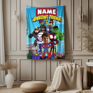 May include: A blue blanket featuring the text "NAME and his AMAZING FRIENDS" in red and yellow. The blanket has cartoon illustrations of superheroes and a child's face in the center. The background shows a cityscape.